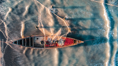 Foto Drone view of a fishing boat with fishermen casting nets