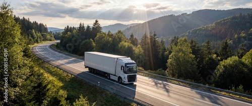 A large white semi-trailer truck travels along a winding asphalt road through a lush green mountain landscape, with tall pine trees and a clear sky.
