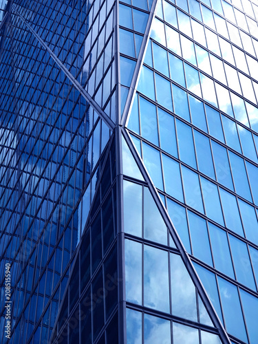 Urban skyscraper with mirrorlike surfaces showcasing clouds and geometric patterns