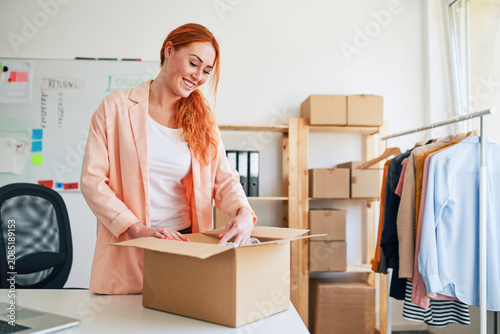 Young woman packing order box in small clothing business