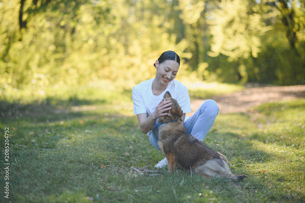 Fototapeta premium Woman petting happy dog in sunny park