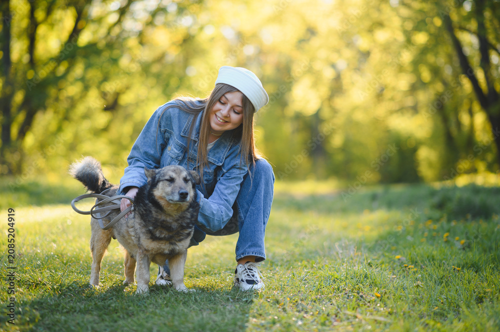Fototapeta premium Young woman petting dog in park enjoying friendship