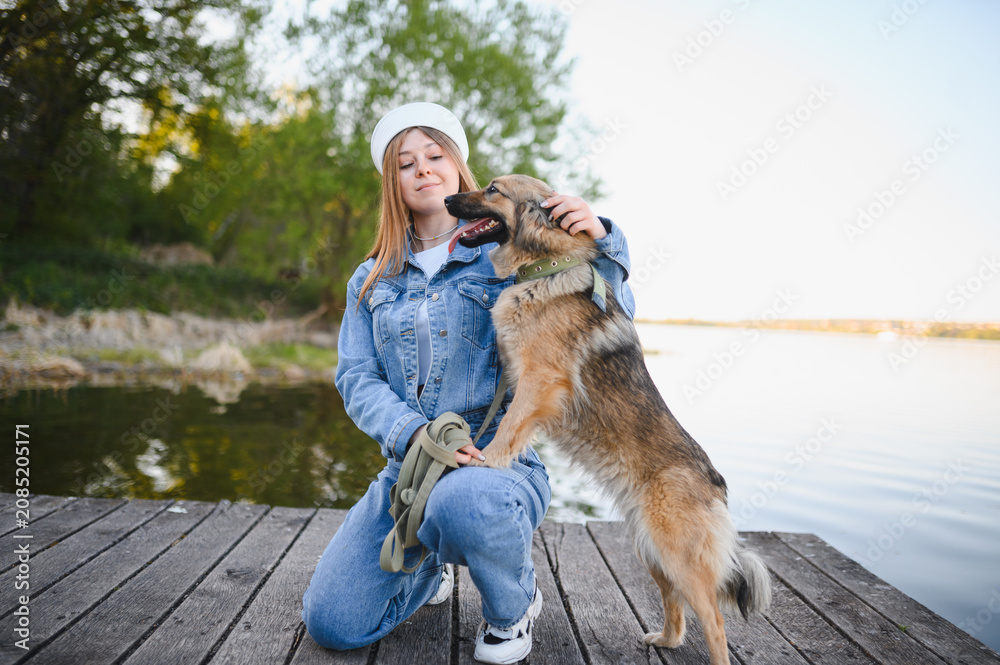 Fototapeta premium Woman petting her dog on a wooden dock
