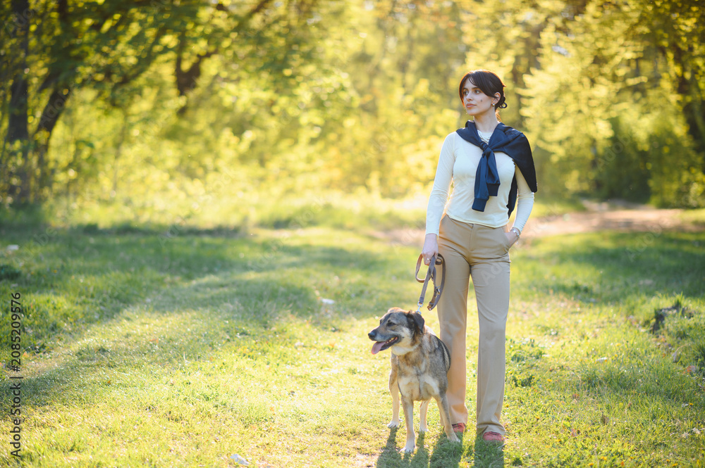 Fototapeta premium Woman walking dog through park enjoying sunny afternoon