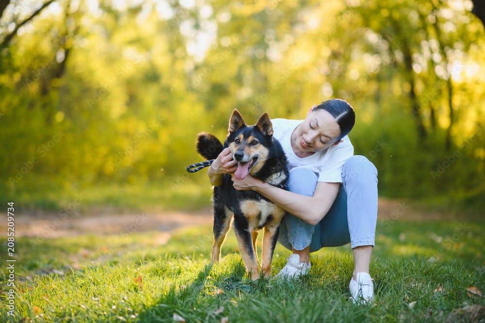 Fototapeta premium Woman hugging dog in park enjoying summer day