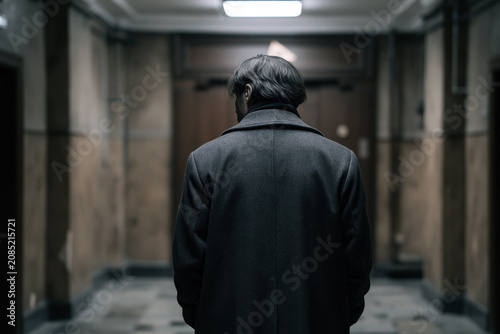 Mysterious Man Waiting in Apartment Lobby with Cinematic Psychological Atmosphere