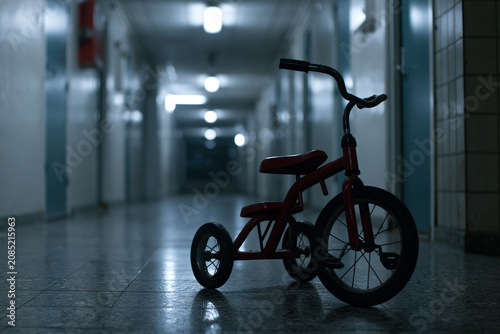 Abandoned Red Tricycle in Empty Apartment Hallway with Psychological Horror Atmosphere
