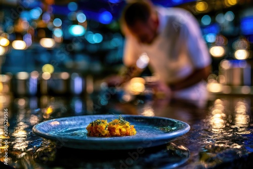 A chef prepares a colorful dish in a dimly lit, bokeh-rich kitchen setting