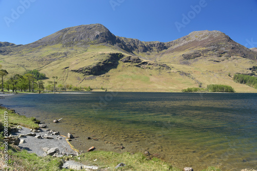 The mountain of High Stile towers above the wooded lake shores of Buttermere in the Lake District