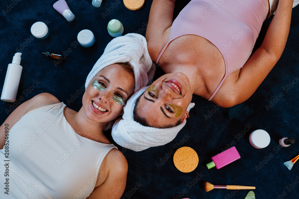 Obraz premium Two happy women lying down, enjoying beauty treatment with under eye patches