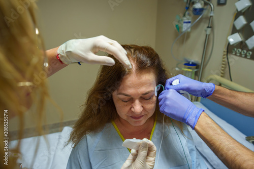 Patient undergoing sleep study, medical staff applying eeg electrodes for polysomnography in hospital
