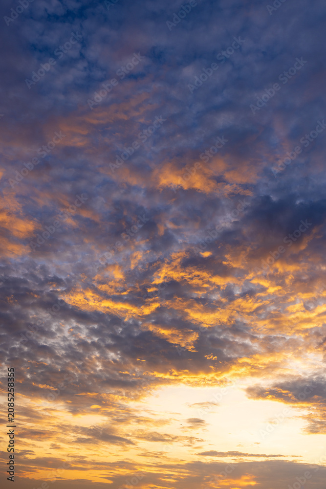 Fototapeta premium Golden Hour Sunset Sky with Dramatic Glowing Clouds,A breathtaking and dramatic sunset sky filled with golden, orange, and yellow clouds, creating a peaceful and inspiring atmosphere at twilight.