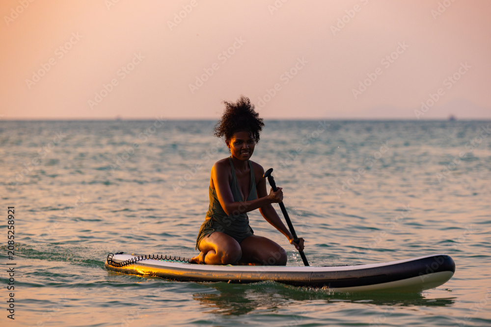Obraz premium Woman Paddleboarding Silhouette at Golden Sunset Sea