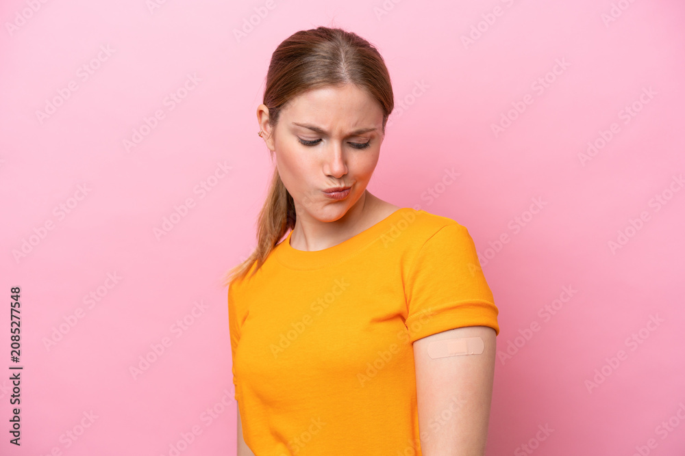 Fototapeta premium Young caucasian woman wearing band aid isolated on pink background with sad expression