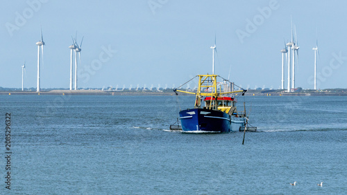 Boat fishing for mussels in the Eastern Scheldt estuary (Zeeland, Netherlands) near the storm surge barrier, built up with wind turbines