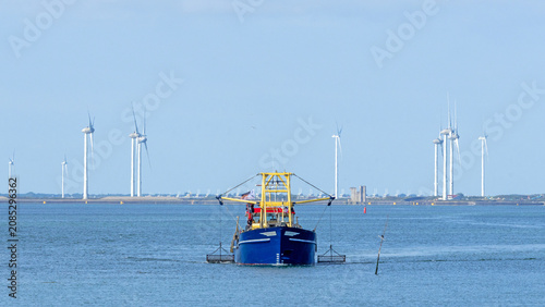 Boat fishing for mussels in the Eastern Scheldt estuary (Zeeland, Netherlands) near the storm surge barrier, built up with wind turbines