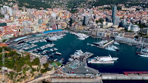 Aerial view of Port Hercules in Monaco with superyachts moored in the marina, Grand Prix grandstands along the quay, high rise buildings of Monte Carlo and the Rocher on the Mediterranean coast.