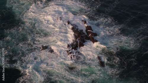 The relentless force of the waves carves patterns into the ancient rocky shore.