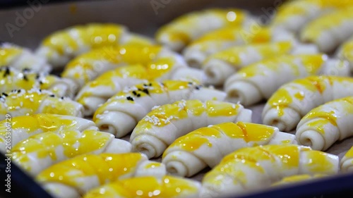 Hands Sprinkling Sesame Seeds and Spices on Homemade Bread Rolls in Baking Tray Before Baking