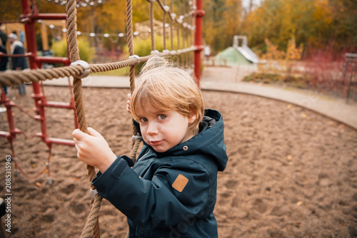 Cuadro en lienzo Curious Toddler Boy Climbing Rope Frame at Outdoor Playground in Autumn — Candid
