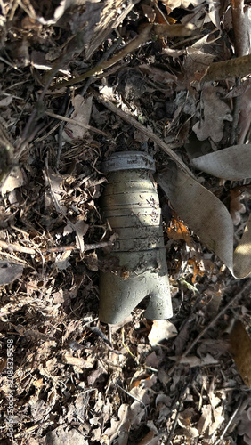 Obraz na płótnie An unexploded cluster submunition, reported as a  3B30 submunition type, lies half-buried on the forest floor