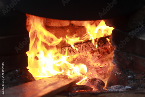 Tableau sur toile Bright orange flames flicker intensely within a rustic brick oven during a traditional outdoor cooking session