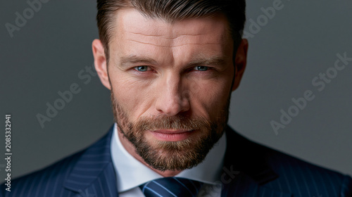 Serious middle aged businessman in navy pinstripe suit looking at camera