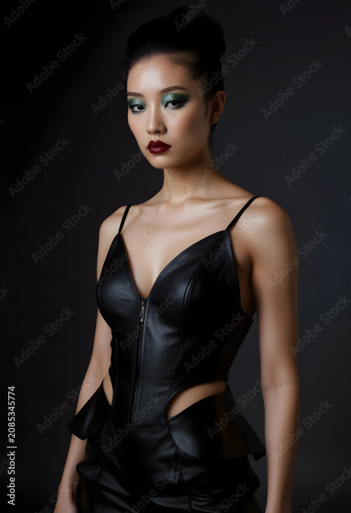 Fototapeta premium Thoughtful woman in black leather dress with bold makeup