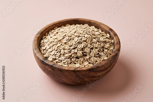Raw Rolled Oats in a Wooden Bowl on a Dusty Pink Background