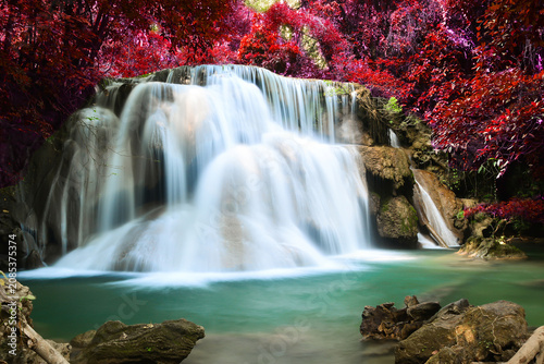 Multi-tiered waterfall flowing into a clear turquoise pool surrounded by red autumn trees with waterfall, turquoise