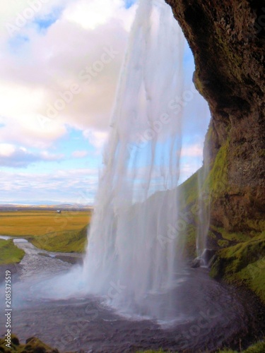 Majestic waterfall dropping from a high rugged cliff above a grassy valley in a scenic northern landscape with waterfall