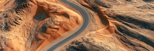 Aerial view of winding asphalt road through hot desert sand dunes