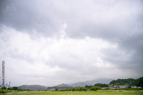 Vast cloudy sky over green field and mountains in Iwate Japan