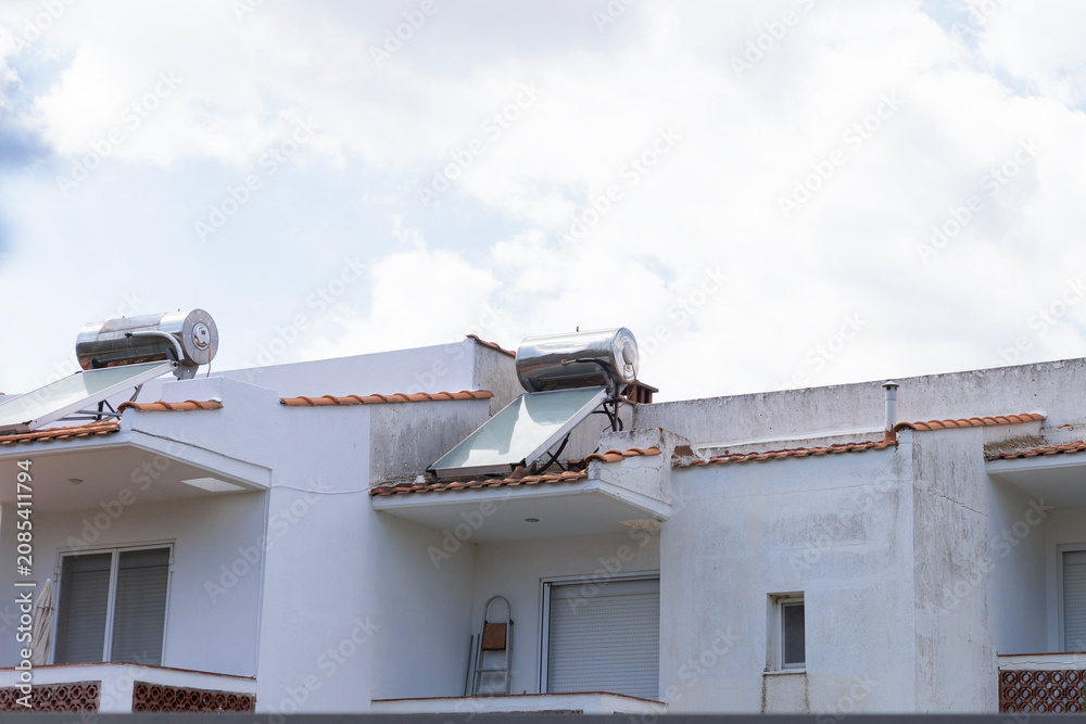 Obraz premium Solar water heaters on white mediterranean building roofs