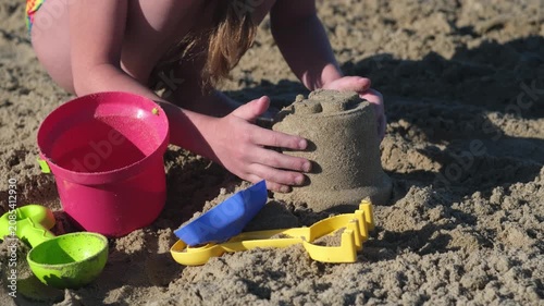 Close up young girl play with sand toys on beach. Summer vacation on ocean or sea coast concept. Kid having fun outdoors on family holidays. build sand castle