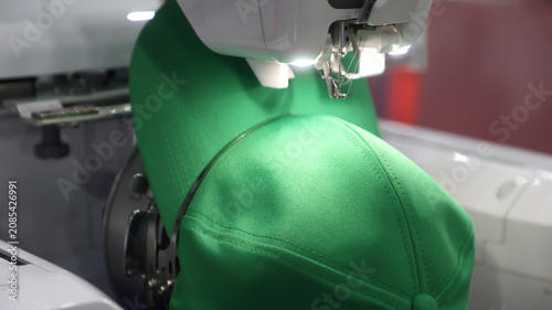Automated embroidery machine stitching a green baseball cap with precision