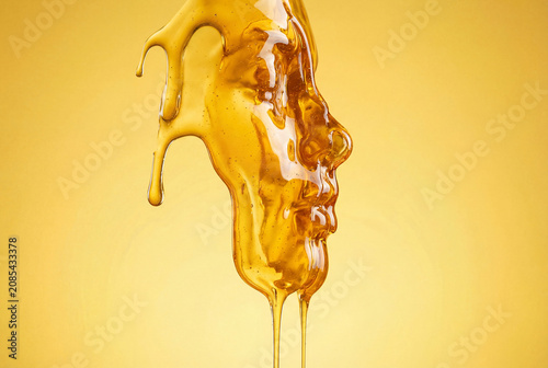 The visual image is an abstract face formed from golden honey, cascading over a bright yellow background. Illustration of health and cosmetology