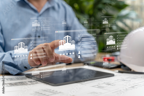Engineer reviewing real estate portfolio on tablet, Property ratings, Valuation for investment planning, Construction certification, Asset management, Efficient digital real estate transactions