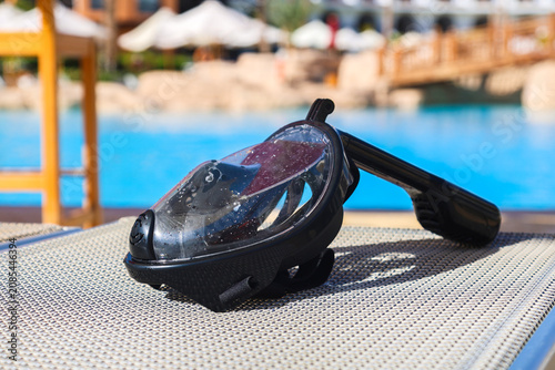Snorkeling mask resting on the mesh of a sun lounger at a tropical beach resort.