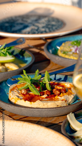 Slika na platnu Appetizer Delight: A close-up view of a delectable appetizer, possibly hummus or a dip, served on a vibrant blue plate, garnished with fresh herbs and spices