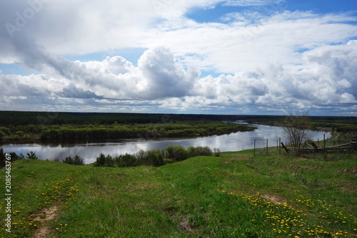 Wide view of a river flowing through a green landscape under a cloudy sky in the daytime