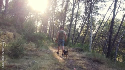 Hombre paseando con su perro por un sendero en el bosque
