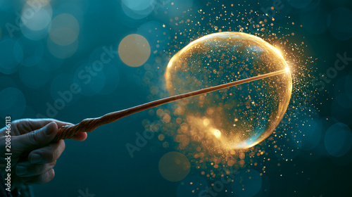 Hand holding a wooden magic wand creating a glowing golden bubble with sparkles.
