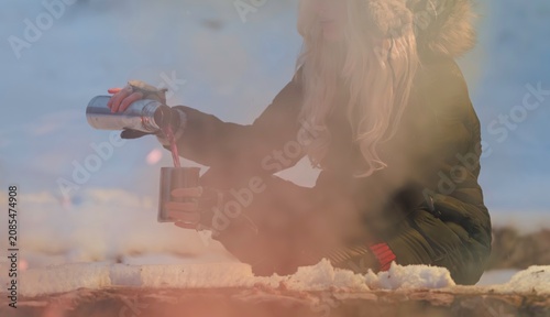 Obraz na plátně A winter adventurer delicately pours a warm beverage into a metallic cup while s