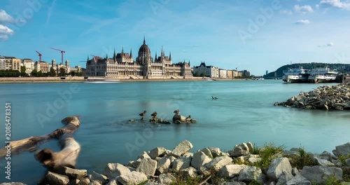 Budapest skyline timelapse with rushing clouds over the Hungarian Parliament Building and smooth flowing water of the Danube River during daytime