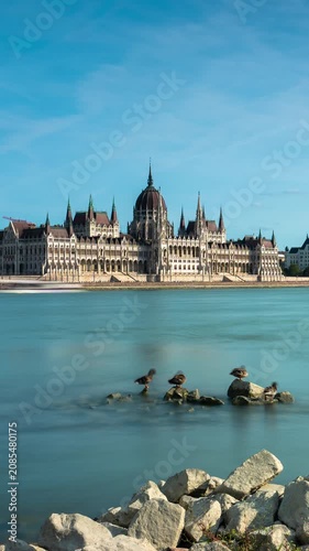 Budapest Parliament timelapse with rushing clouds over the Danube River during a bright sunny day, featuring moving shadows across gothic architecture