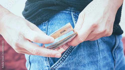 Foto A man takes out euro banknotes from the pocket of his jeans, toned