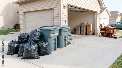Preparing for a move or decluttering with trash bags and bins by the garage