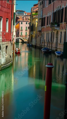 Venice canal timelapse featuring shifting shadows over green water and historic italian architecture with a blurred boat passing by a narrow waterway