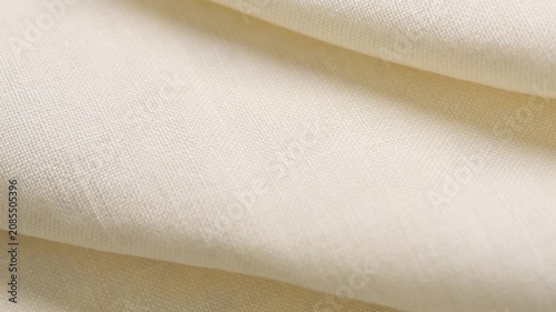 Natural cotton with linen fabric folds, white homespun vintage fabric, natural eco folded linen background. Bio textile material backdrop, canvas top view, close up, rotating. 